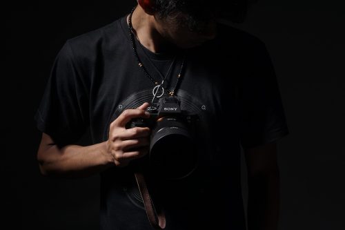 Man standing against black background holding a camera
